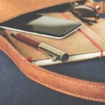 Stylish leather bag with a fountain pen, smartphone, and notebook on display.